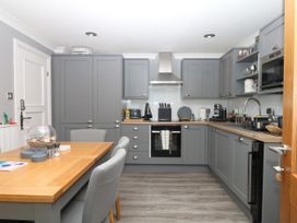 A kitchen with a dining table and modern appliances at 12 Courtyard Cottage at Sheplegh Court, Totnes