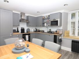 A kitchen with grey cabinets and a dining table at 12 Courtyard Cottage at Sheplegh Court in Totnes