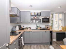 A kitchen with cabinets and appliances at 12 Courtyard Cottage at Sheplegh Court Totnes
