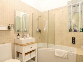 A bathroom with a bathtub and shower at 12 Courtyard Cottage at Sheplegh Court in Totnes