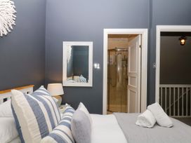 A bedroom with a bed, mirror, and an adjoining bathroom at 12 Courtyard Cottage at Sheplegh Court in Totnes