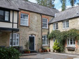 A stone building with windows and door framed by potted plants at 12 Courtyard Cottage at Sheplegh Court Totnes