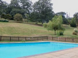 A swimming pool with surrounding fence and landscape at 12 Courtyard Cottage at Sheplegh Court in Totnes