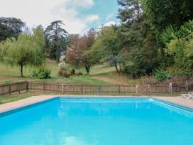An outdoor area with a swimming pool and surrounding grass at 12 Courtyard Cottage at Sheplegh Court in Totnes