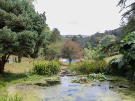 A garden with a pond and a pool in the background at 12 Courtyard Cottage at Sheplegh Court, Totnes