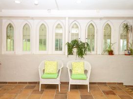 A conservatory with armchairs and plants at 12 Courtyard Cottage at Sheplegh Court, Totnes