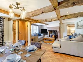 A dining area and living room with a fireplace and television at The Quirky Cottage Eamont Bridge near Ullswater
