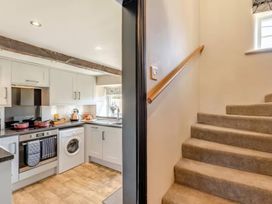 A kitchen with appliances and a staircase at The Quirky Cottage in Eamont Bridge near Ullswater