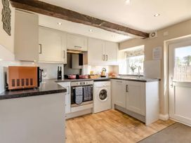 A kitchen with appliances and a window at The Quirky Cottage in Eamont Bridge near Ullswater