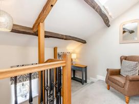 A landing with staircase and armchair at The Quirky Cottage in Eamont Bridge near Ullswater