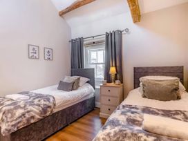 A bedroom with two single beds and a window at The Quirky Cottage in Eamont Bridge near Ullswater