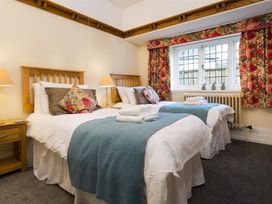A bedroom with two beds and decorative curtains at White Gables in Ambleside