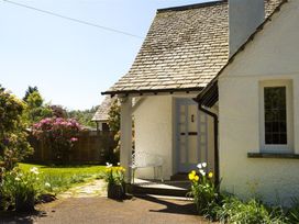 A house entrance with a bench and flower pots at White Gables in Ambleside