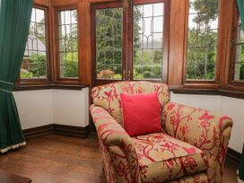 A sitting room with a floral armchair and large windows at White Gables in Grasmere