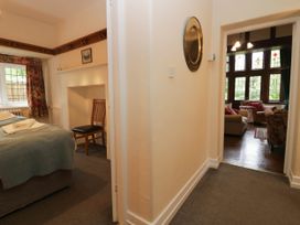 A bedroom with a bed and chair leading to a living room at White Gables Grasmere