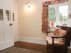 An entryway with a wooden settee and floral curtains at White Gables in Grasmere