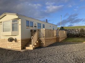 A static caravan with a wooden deck and steps at Beautifully Presented 2 Bedroom Static Caravan in Monreith near Whithorn