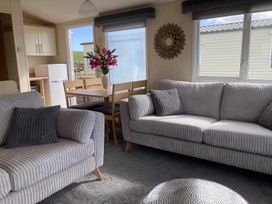A living room with a sofa and a dining area at Beautifully Presented 2 Bedroom Static Caravan Monreith near Whithorn