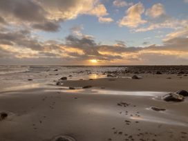 A beach with rocks and ocean waves at sunset at Beautifully Presented 2 Bedroom Static Caravan Monreith near Whithorn