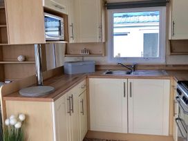 A kitchen with a sink and microwave at Beautifully Presented 2 Bedroom Static Caravan in Monreith near Whithorn
