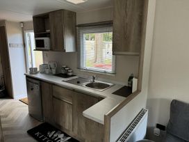 A kitchen with a sink and microwave at West Lawn 47 Haggerston Castle Paddock Views Haggerston
