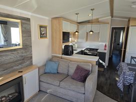 A living room with a sofa and kitchen area at 3 Bed-Sleeps 8-Free Parking-5 Min to Beach in Embo near Dornoch