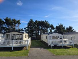 Two mobile homes with decks in a grassy area at 3 Bed-Sleeps 8-Free Parking-5 Min to Beach Embo near Dornoch