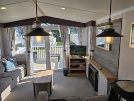 A living room with a sofa, coffee table, and television at 3 Bed-Sleeps 8-Free Parking-5 Min to Beach in Embo near Dornoch
