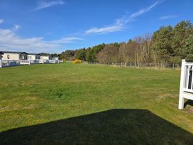 A view of mobile homes and grass area at 3 Bed-Sleeps 8-Free Parking-5 Min to Beach in Embo near Dornoch