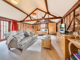 A living room with a sofa and television at Barn Conversion Sleeps 2 with Parking in Diss
