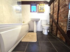 A bathroom with a bath tub, wash basin and toilet at Barn Conversion Sleeps 2 with Parking in Diss