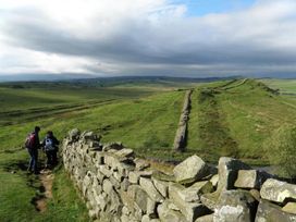 Hikers on a path by a stone wall along Hadrian's Wall near Haltwhistle
