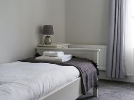 A bedroom with a bed, lamp, and towels at East House-Sleeps 5-Pet friendly-Garden-Parking in Stakeford