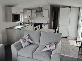 A kitchen with a couch, table, and appliances at 3 Bedroom Cabin Sleeps 6 - Shared Pool & Shared Hot Tub, Flamingo Land Resort near Malton