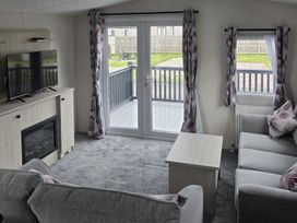 A living room with a television and fireplace at 3 Bedroom Cabin Sleeps 6 - Shared Pool & Shared Hot Tub, Flamingo Land Resort near Malton