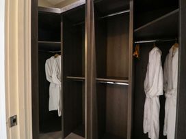 A closet with hanging robes and empty shelves at Northumberland Luxury Stays - The Chivits in West Chevington near Amble
