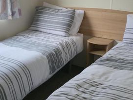 A bedroom with two single beds and a nightstand at Port Haverigg Cabin Sleeps 4 Steel Green near Haverigg