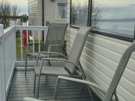 A seating area with chairs on a deck at Port Haverigg Cabin Sleeps 4, Steel Green near Haverigg