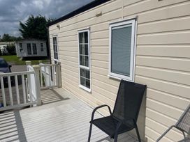 A deck with a chair and windows at 2 Bed Lodge Sleeps 5 - Pet Friendly, WiFi, Parking, Skegness