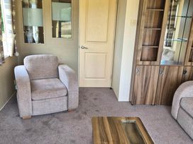 A living room with an armchair and a cabinet at Cabin - Sleeps 6 - Outdoor Pool and Parking, Cenarth