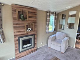 A living room with a fireplace and an armchair at Cabin - Sleeps 6 - Outdoor Pool and Parking, Cenarth