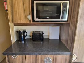A kitchen with a microwave, kettle, and toaster at Cabin - Sleeps 6 - Outdoor Pool and Parking in Cenarth