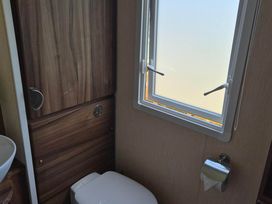 A bathroom with a toilet and window at Cabin - Sleeps 6 - Outdoor Pool and Parking Cenarth