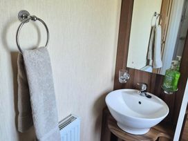 A bathroom with a hand wash basin and a towel on the towel ring at Cabin - Sleeps 6 - Outdoor Pool and Parking Cenarth