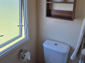 A bathroom with a toilet and window at Cabin - Sleeps 6 - Outdoor Pool and Parking in Cenarth