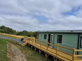 A mobile home with a wooden deck and a car parked at Cabin - Sleeps 6 - Outdoor Pool and Parking in Cenarth