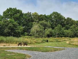A picnic table and benches near a grassy area at Cabin - Sleeps 6 - Outdoor Pool and Parking in Cenarth