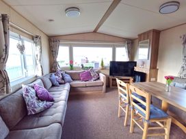 A living room with a sofa and television at Snowdonia Sunbeach Holiday Sea and Mountain view Llwyngwril