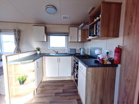 A kitchen with cabinets and appliances at Snowdonia Sunbeach Holiday Sea and Mountain view, Llwyngwril