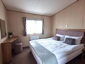 A bedroom with a bed and a mirror at Snowdonia Sunbeach Holiday Sea and Mountain view, Llwyngwril